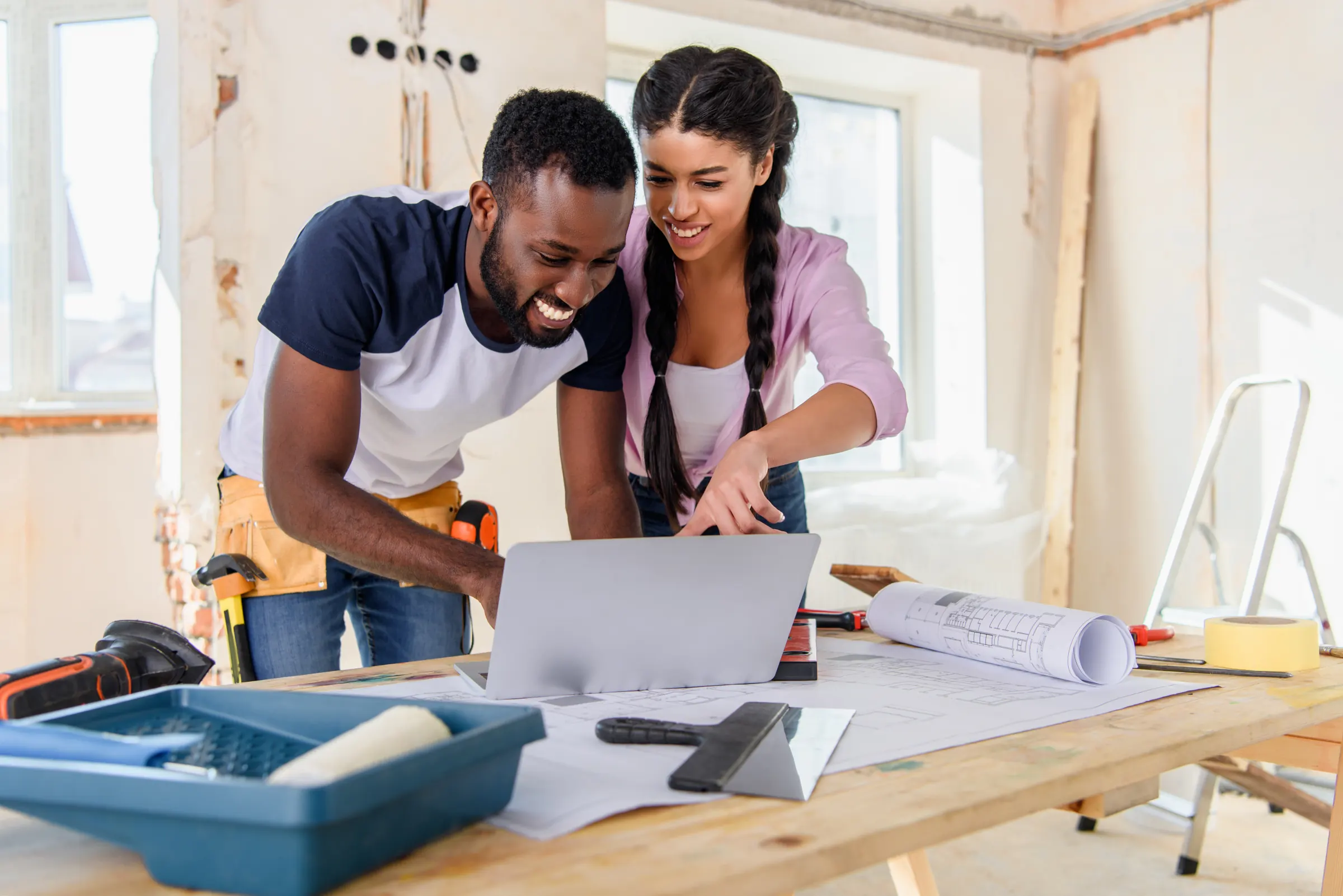 Two people reviewing home renovation plans on a laptop